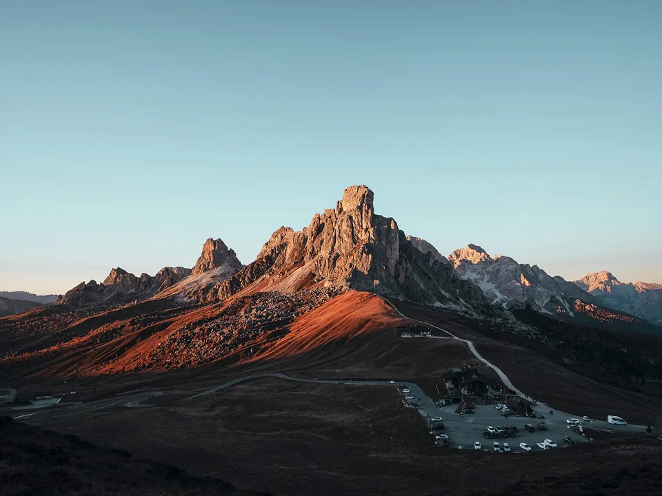 Berglandschaft im warmen Licht mit markanten Gipfeln und Tal im Vordergrund.