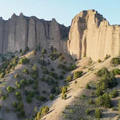 Markante Felsformationen in trockener Canyonlandschaft mit vereinzelter Vegetation.