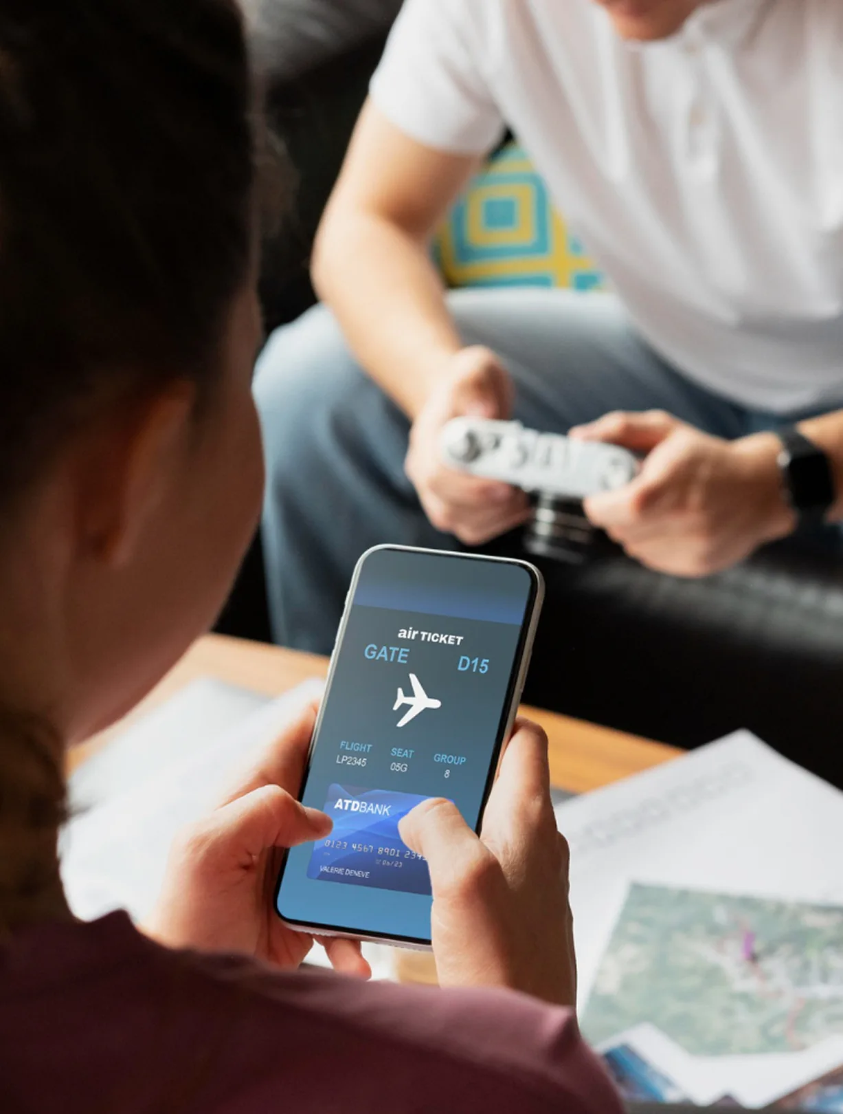 Person hält Smartphone mit digitalem Flugticket während im Hintergrund Reisedokumente vorbereitet werden.