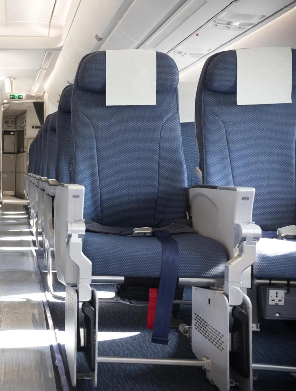 Sitzreihe in einer Flugzeugkabine mit Sicherheitsgurten und Gang entlang der Plätze.