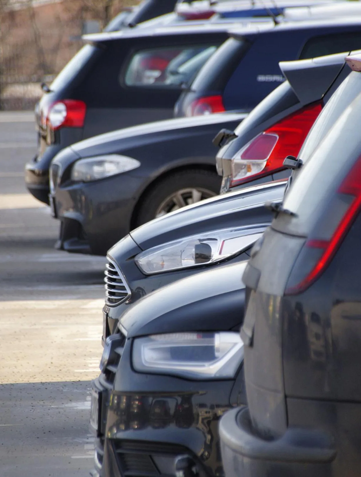 Reihe parkender Autos auf einem Parkplatz aus seitlicher Perspektive.