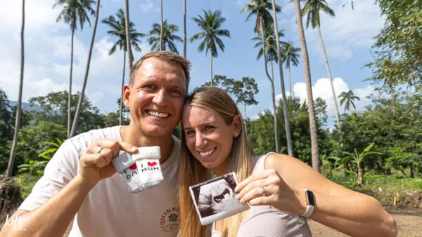 Daniel und Jessi in Thailand halten Ultraschallbild und Babysocken in die Kamera